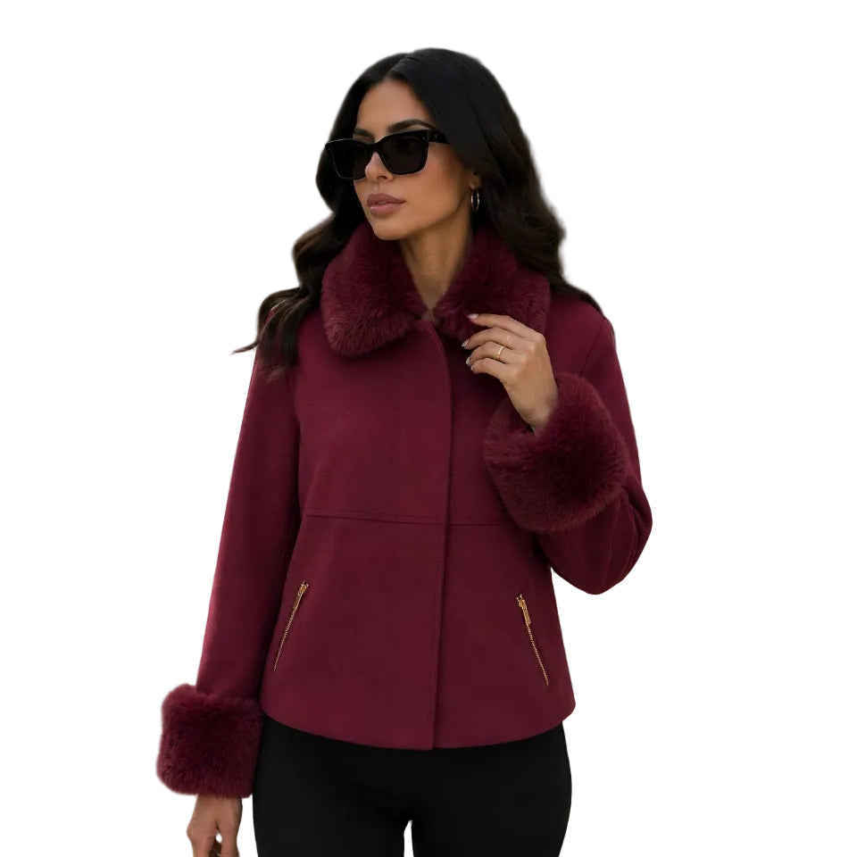 A woman modeling a burgundy faux-shearling jacket with plush faux-fur trim on the collar, cuffs, and hem, featuring gold zipper details on the front, set against a plain white background.
